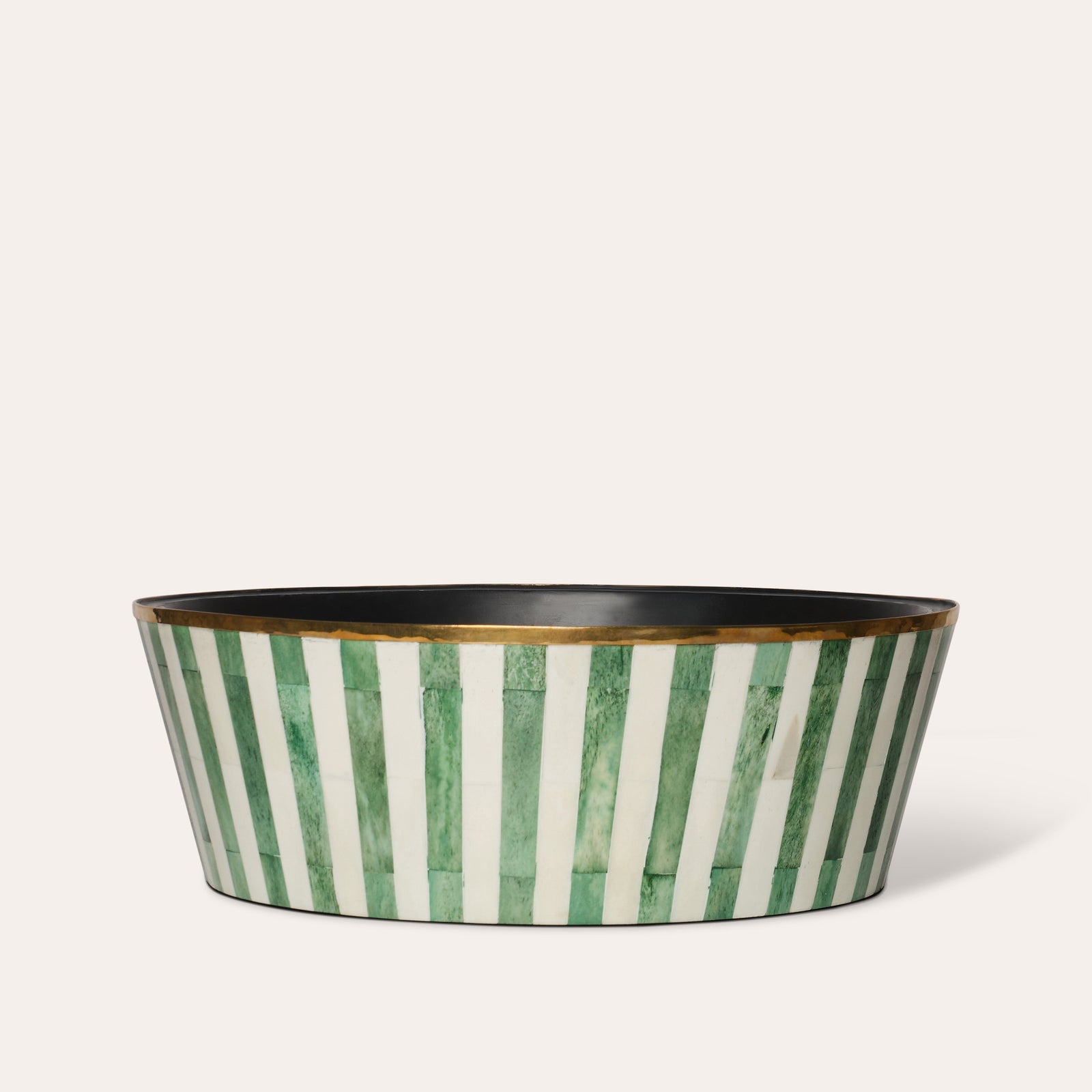 A large round planter with green and white striped pattern and a brass rim, with a felt-lined base.