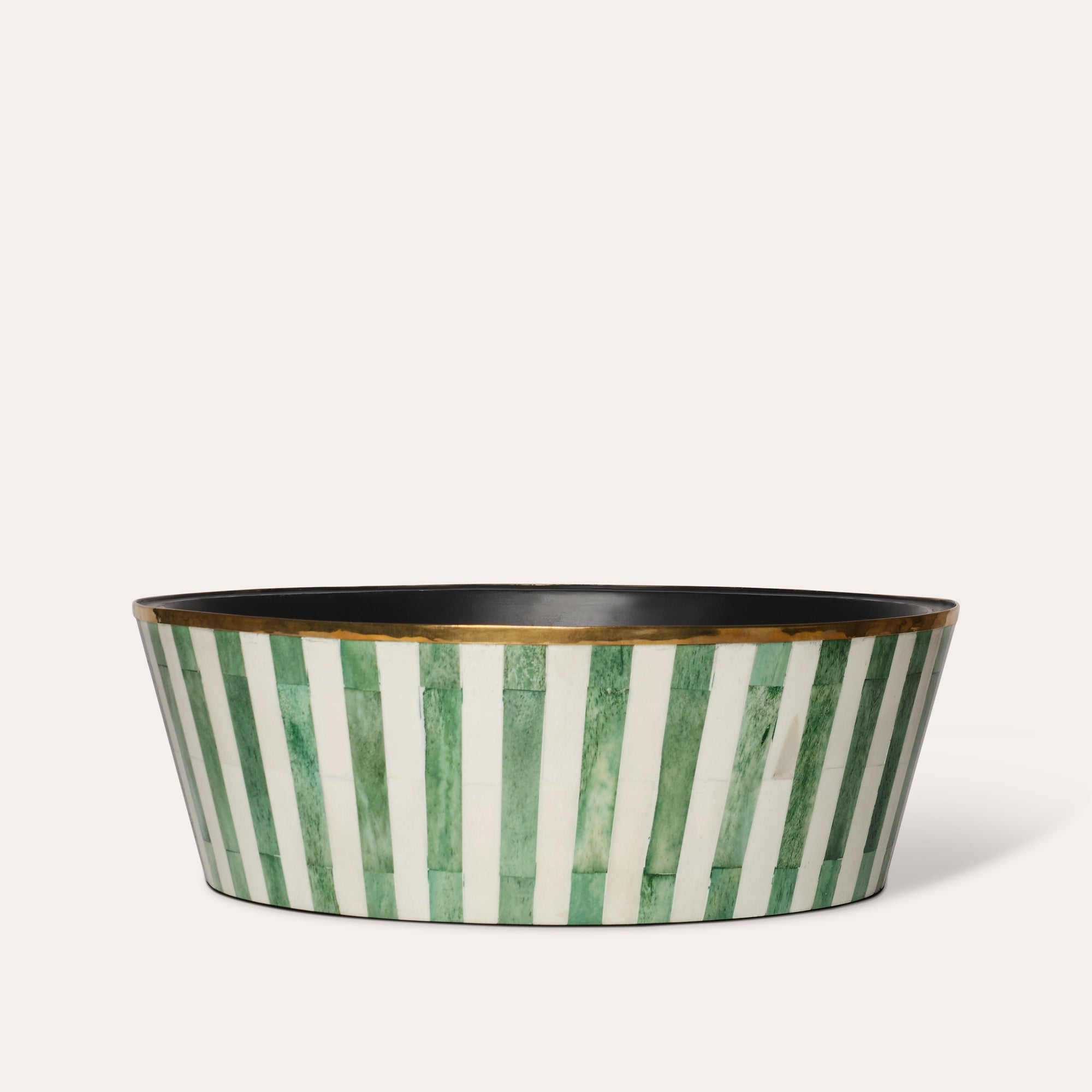 A large round planter with green and white striped pattern and a brass rim, with a felt-lined base.