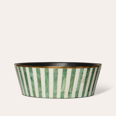 A large round planter with green and white striped pattern and a brass rim, with a felt-lined base.