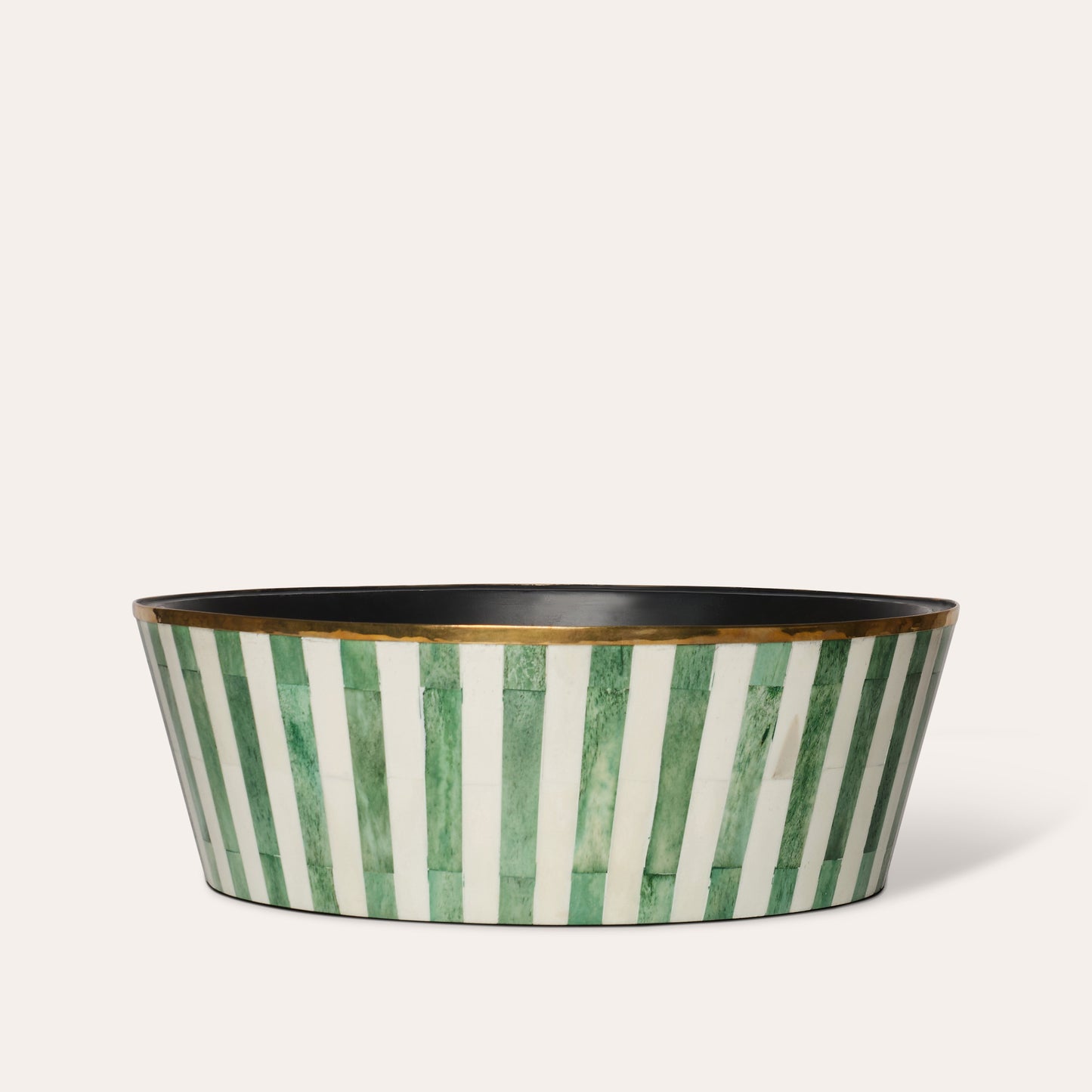 A large round planter with green and white striped pattern and a brass rim, with a felt-lined base.