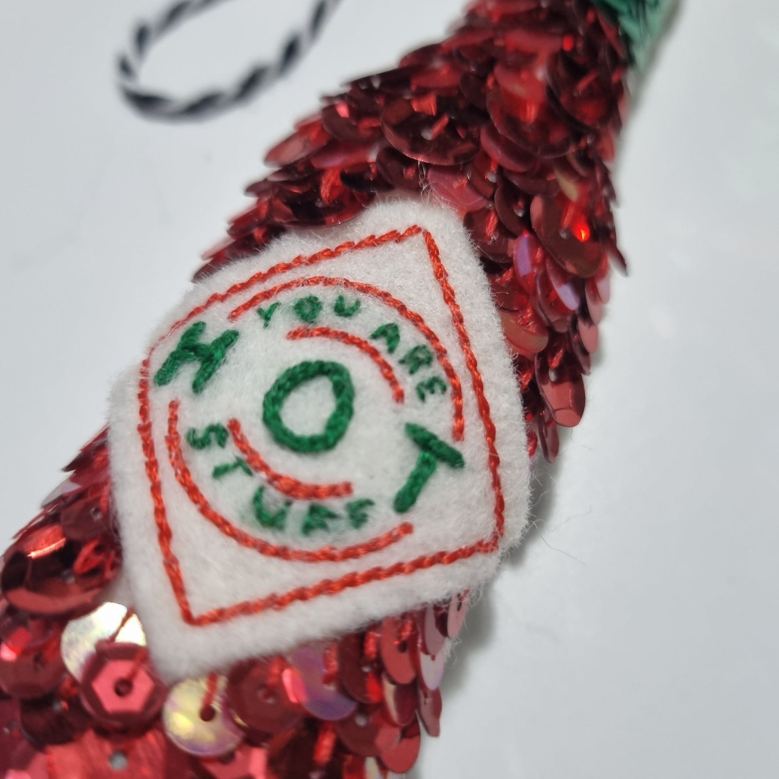 a sequinned tabasco bottle with a label saying you are hot stuff