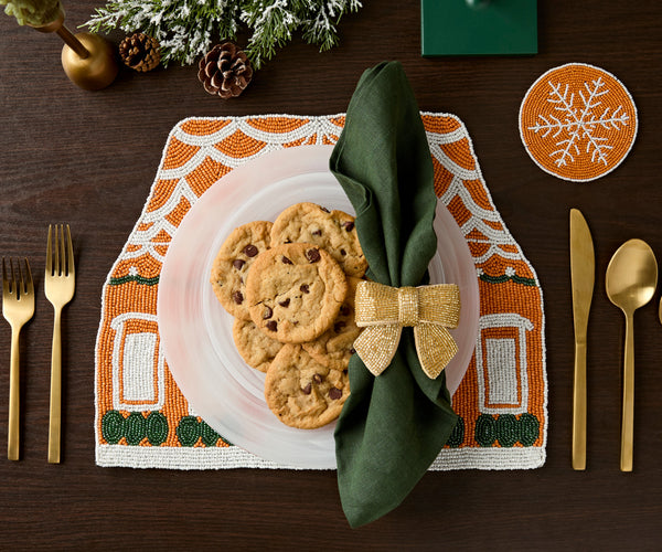 Gingerbread house beaded placemat set with a plate of cookies, a green napkin and a gold bow napkin ring