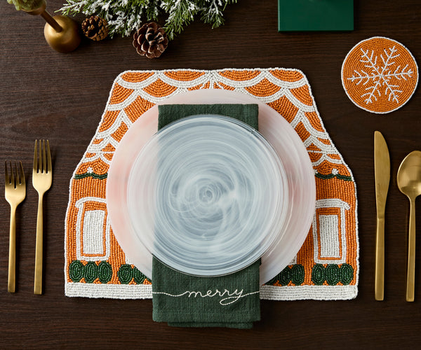 Overhead view of a holiday table set on a gingerbread house beaded placemat