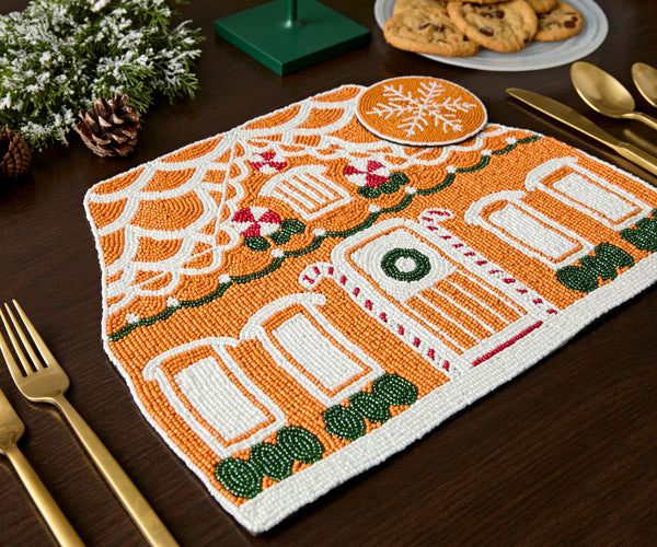 Gingerbread house beaded placemat beside a beaded snowflake coaster on a dark wood table