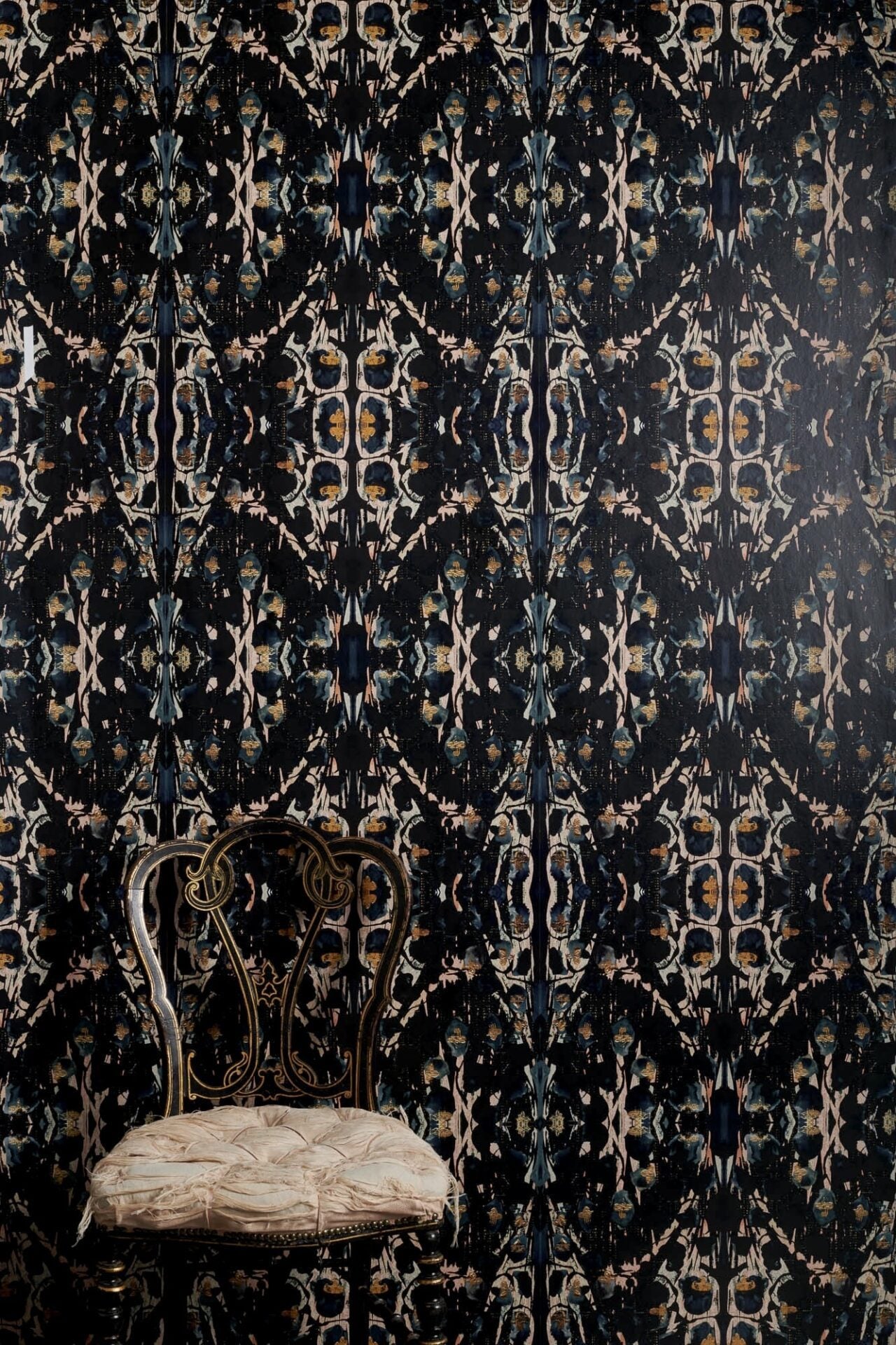 Siouxsie dark patterned wallpaper with blue-black base and layered gold and pink tones in semi-gloss finish