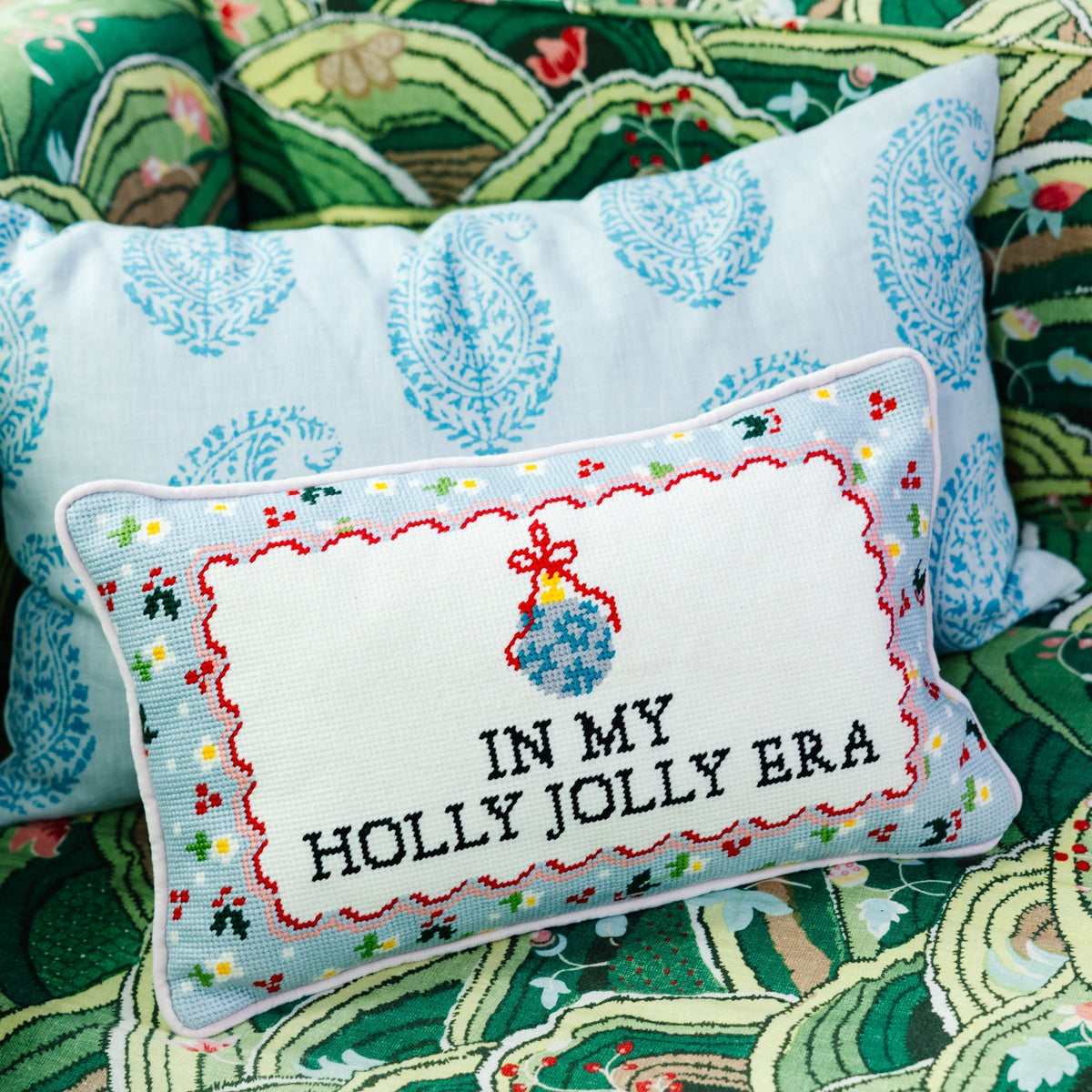 Decorative pillow with 'In My Holly Jolly Era' text on a patterned fabric background