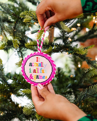 Person holding a colorful ornament with text on a Christmas tree