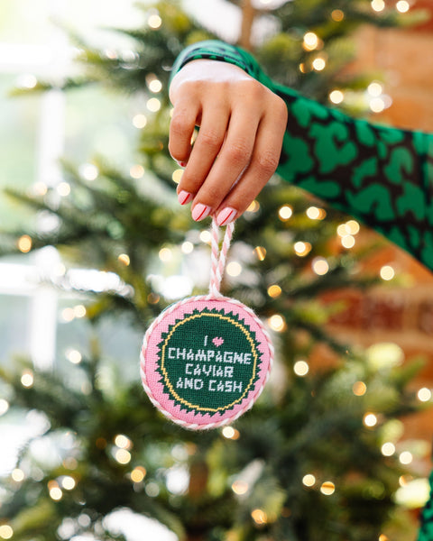 Hand holding a Christmas ornament with text in front of a decorated tree