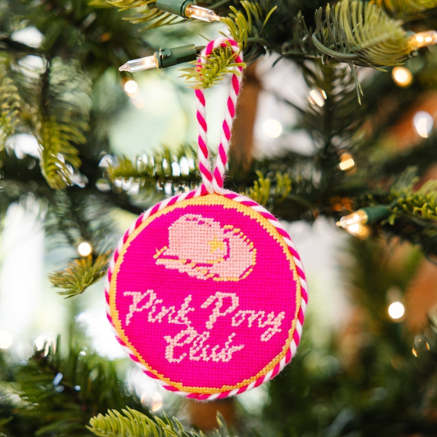 Pink ornament with 'Pink Pony Club' text on a Christmas tree