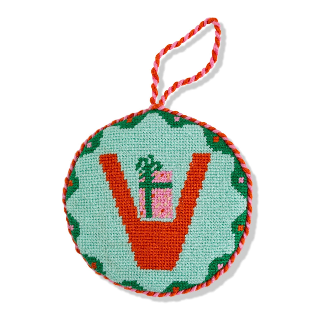Round needlepoint ornament with a design of a gift and tree on a light blue background.