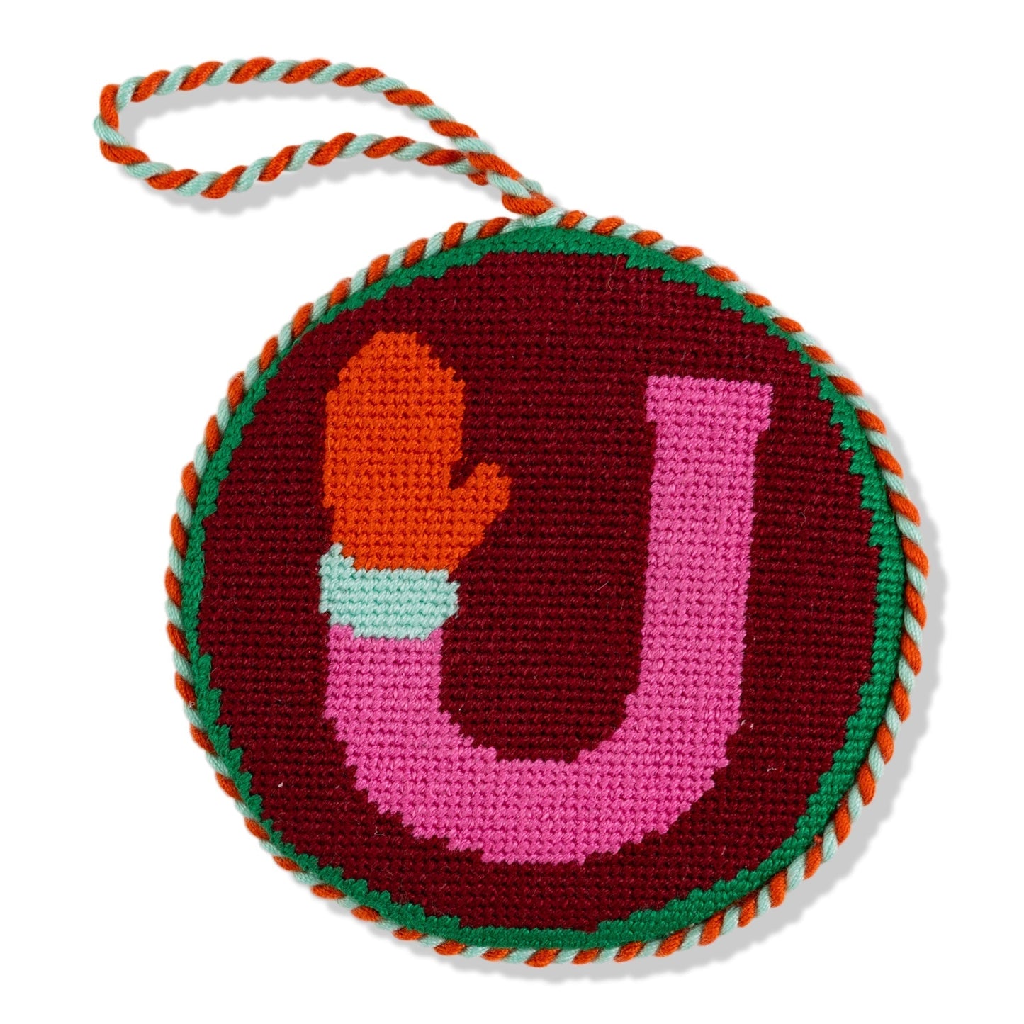 Circular knitted toy with letter 'U' and colorful border on a white background