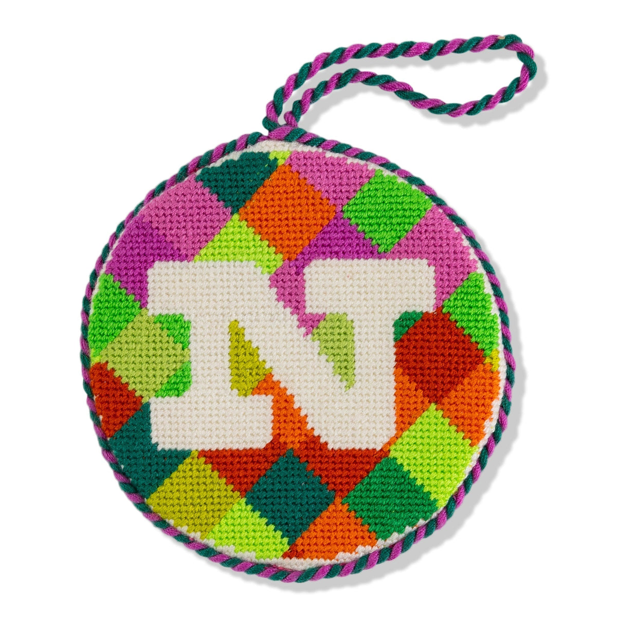 Colorful checkered round needlepoint ornament with 'MT' in the center on a white background