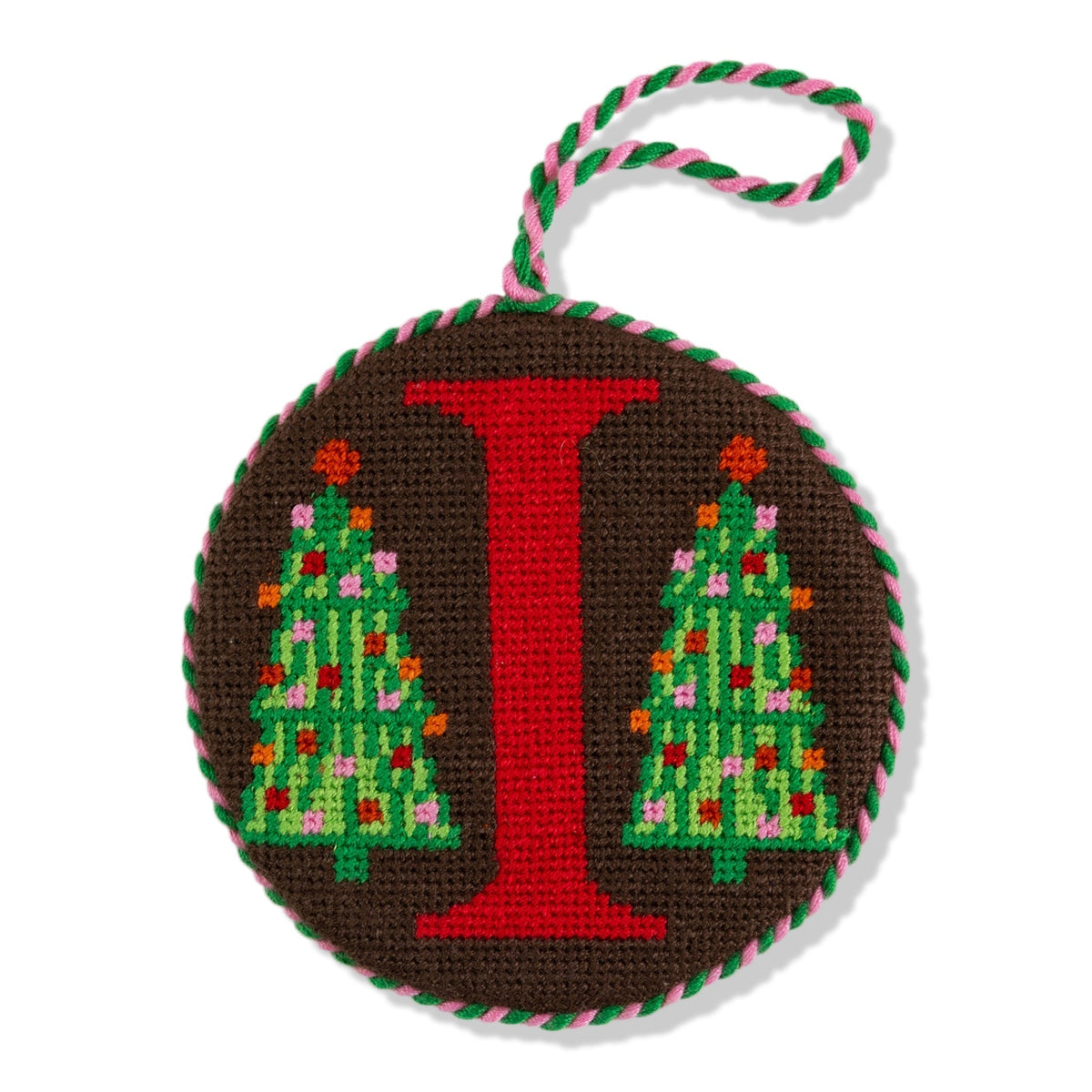 Decorative ornament with letter 'I' and Christmas tree design on a brown background.