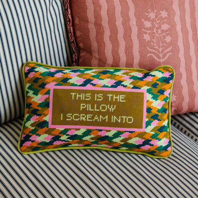 Decorative pillow with geometric pattern and text on a striped sofa