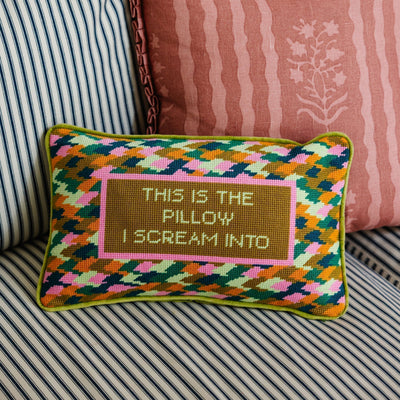 Decorative pillow with geometric pattern and text on a striped sofa