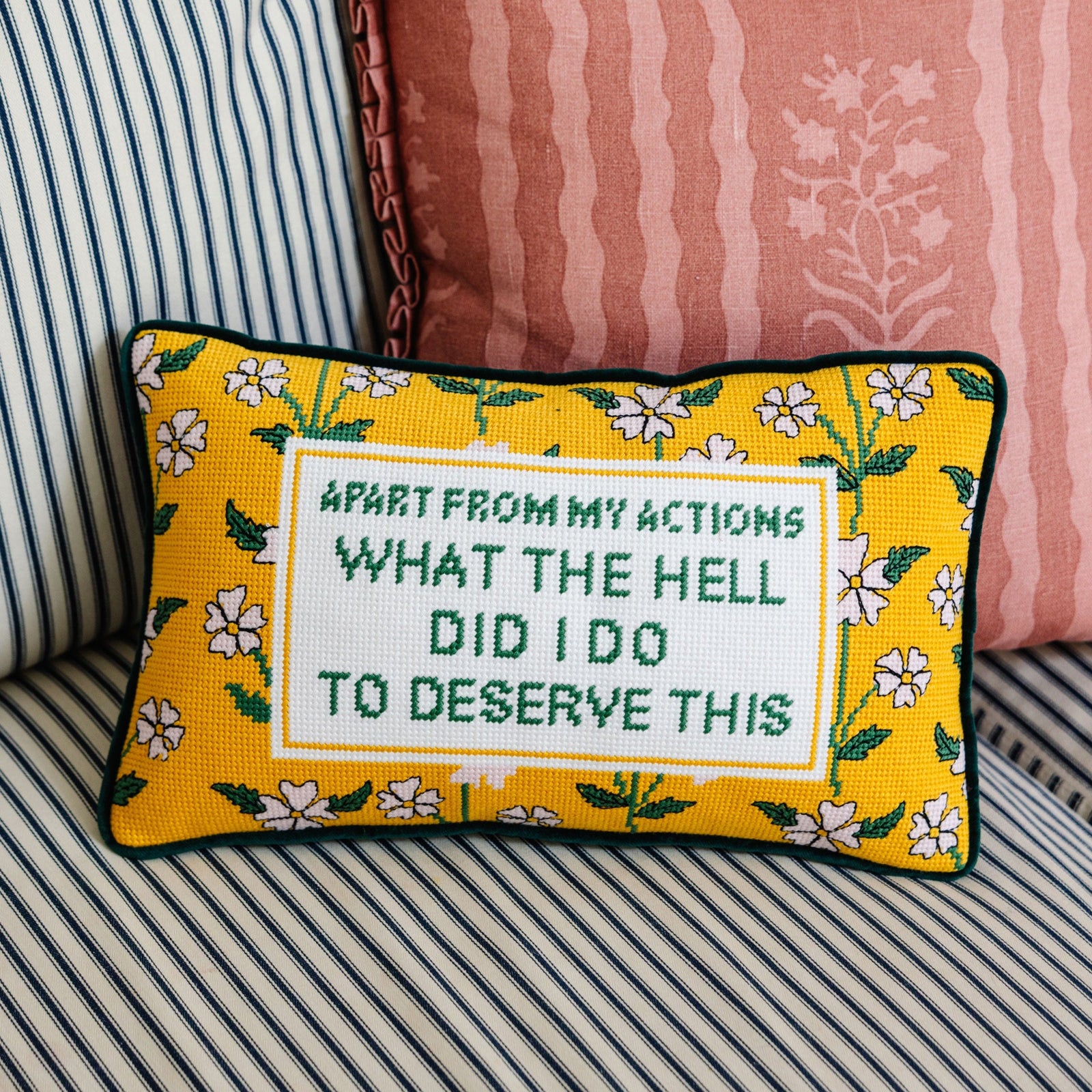 Decorative pillow with text and floral pattern on a striped sofa