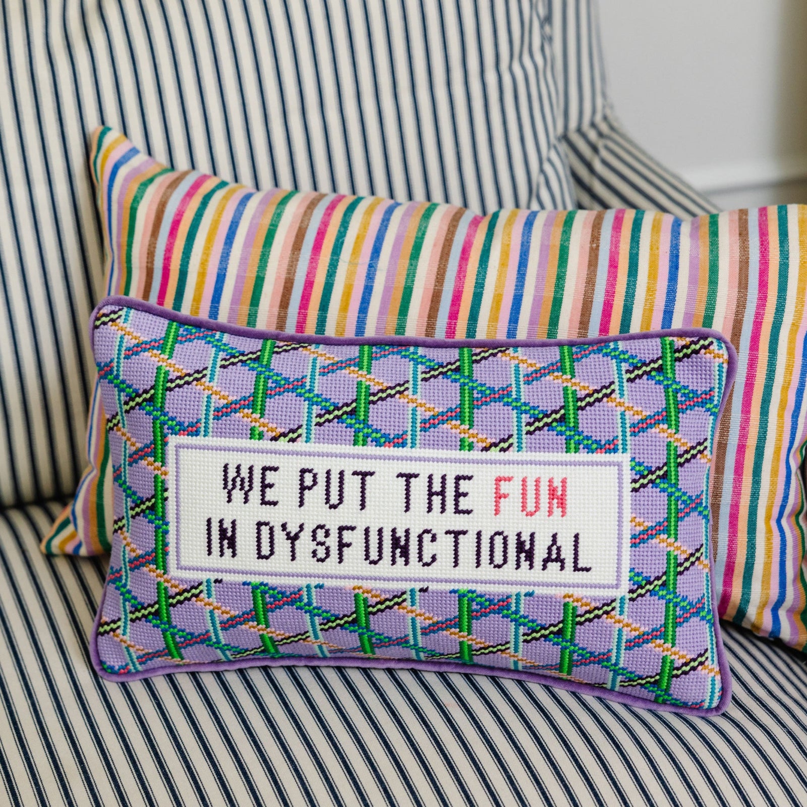 Decorative pillow with colorful text on a striped couch