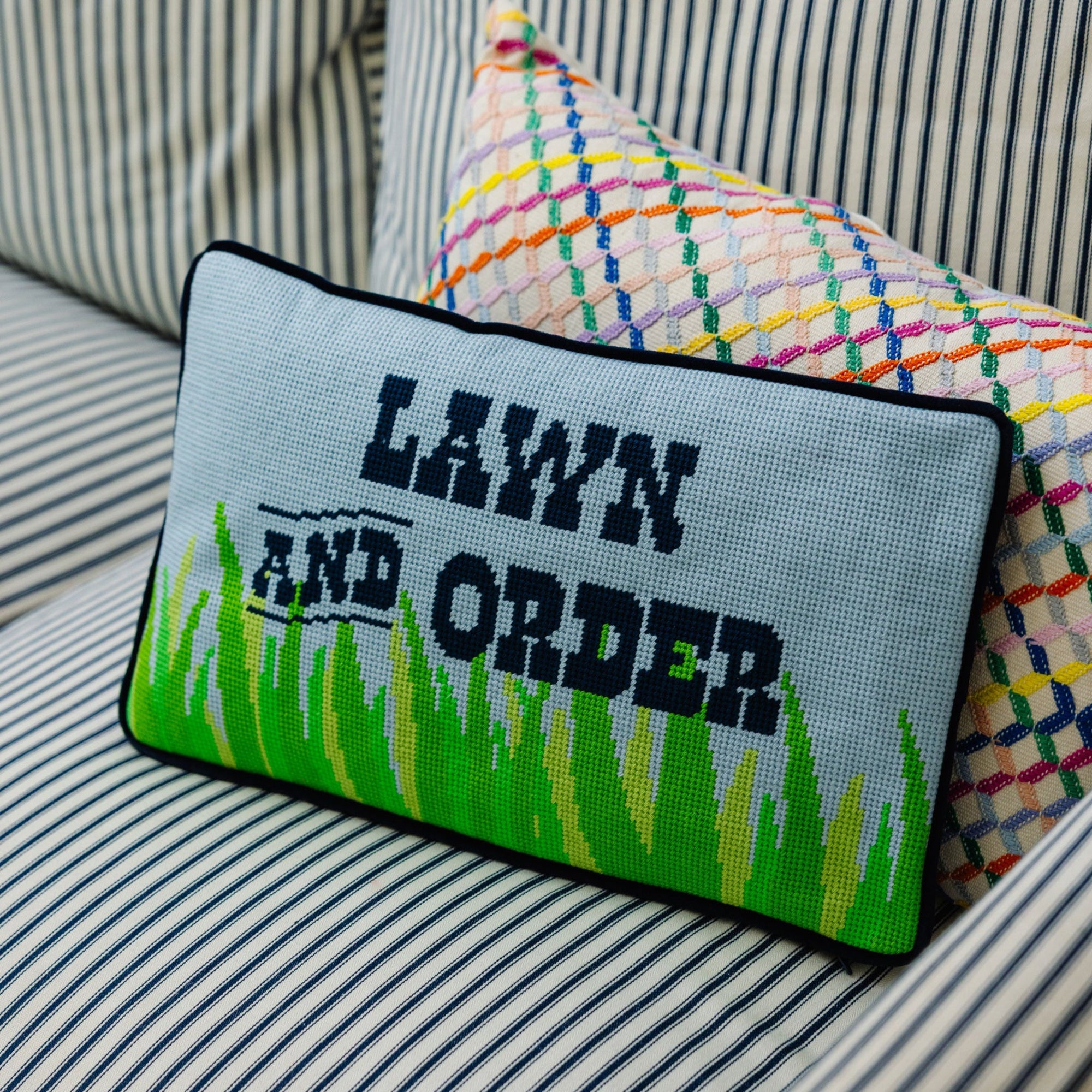 Decorative pillow with 'Lawn and Order' text on a striped sofa