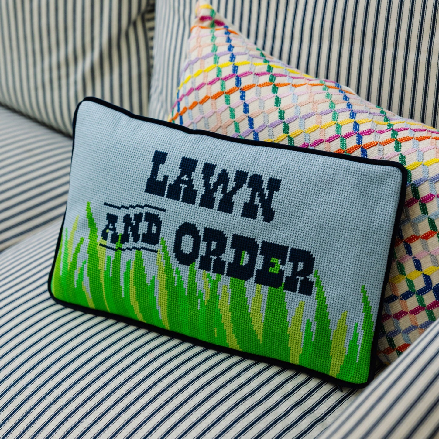 Decorative pillow with 'Lawn and Order' text on a striped sofa