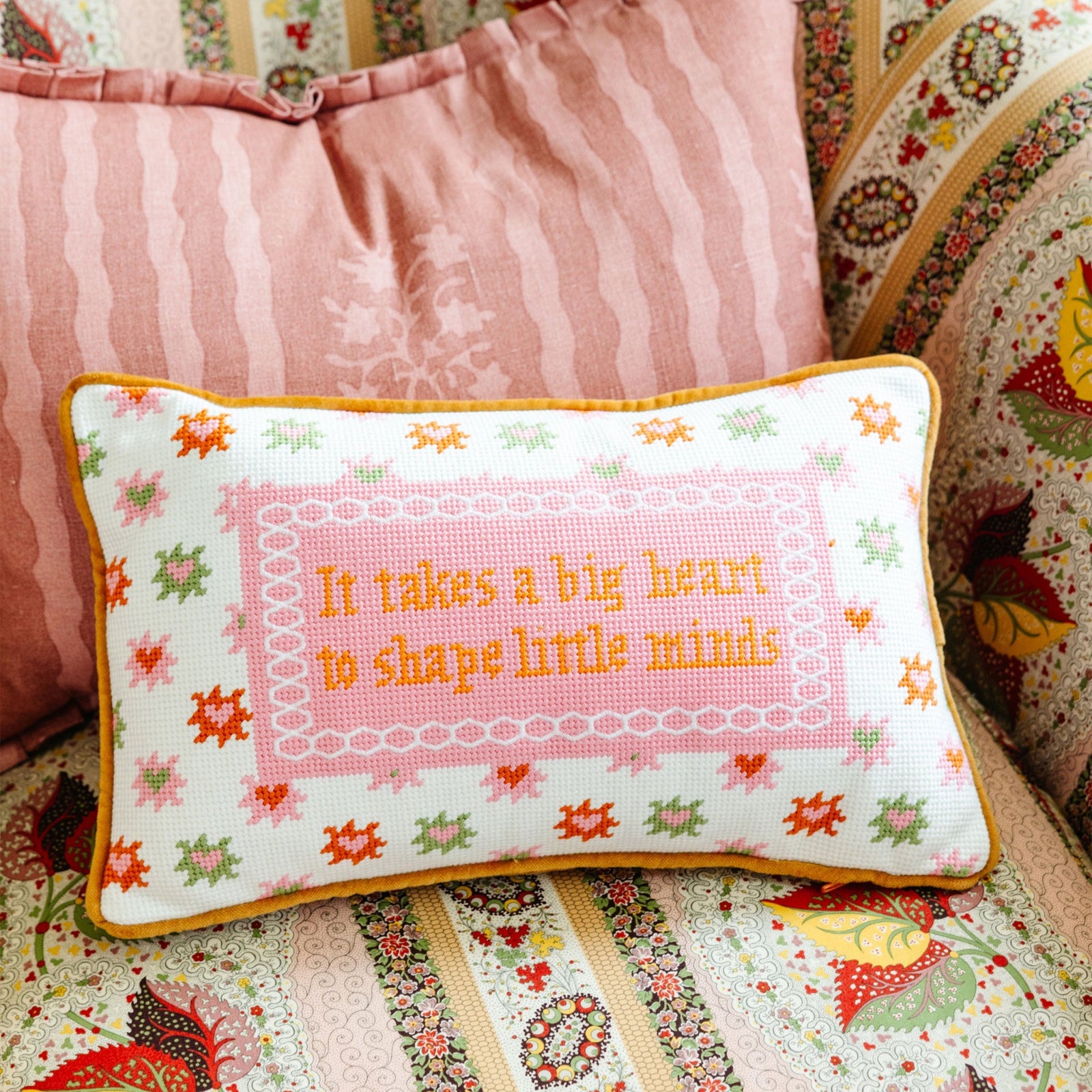 Decorative pillow with embroidered text on a floral-patterned couch