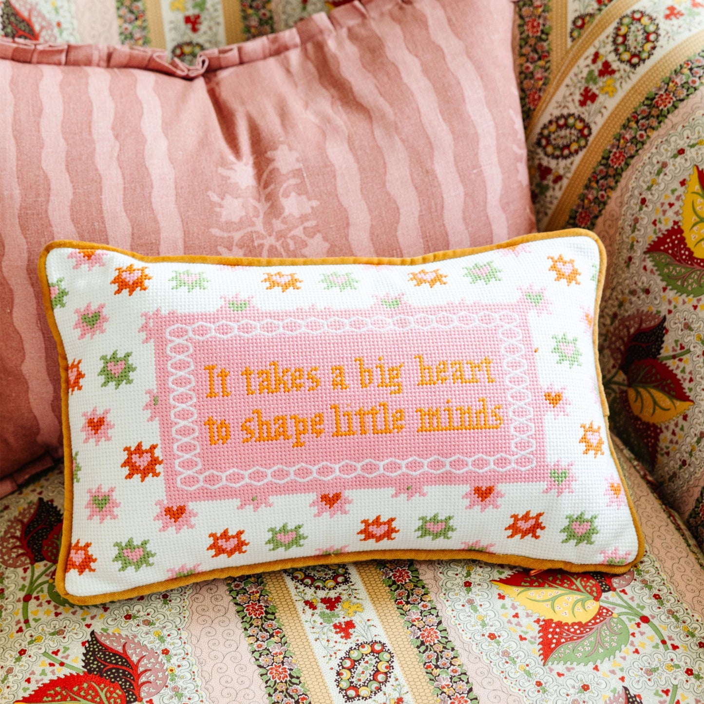 Decorative pillow with embroidered text on a floral-patterned couch