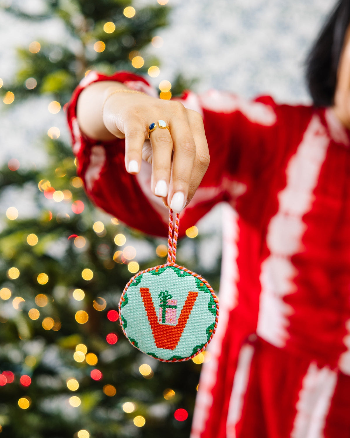 Person holding a Christmas ornament with a tree in the background