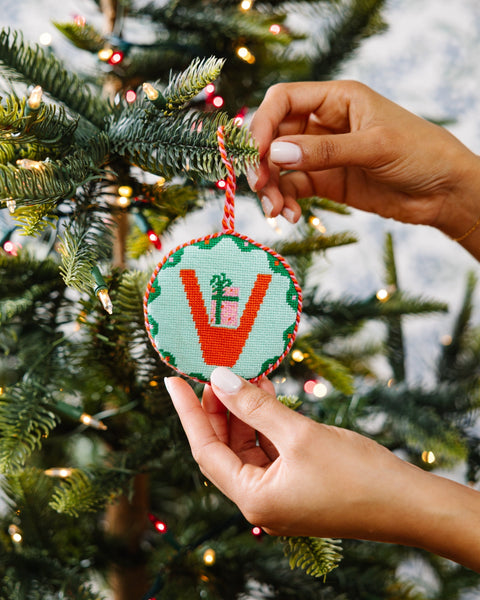 Hand holding a decorative ornament in front of a Christmas tree