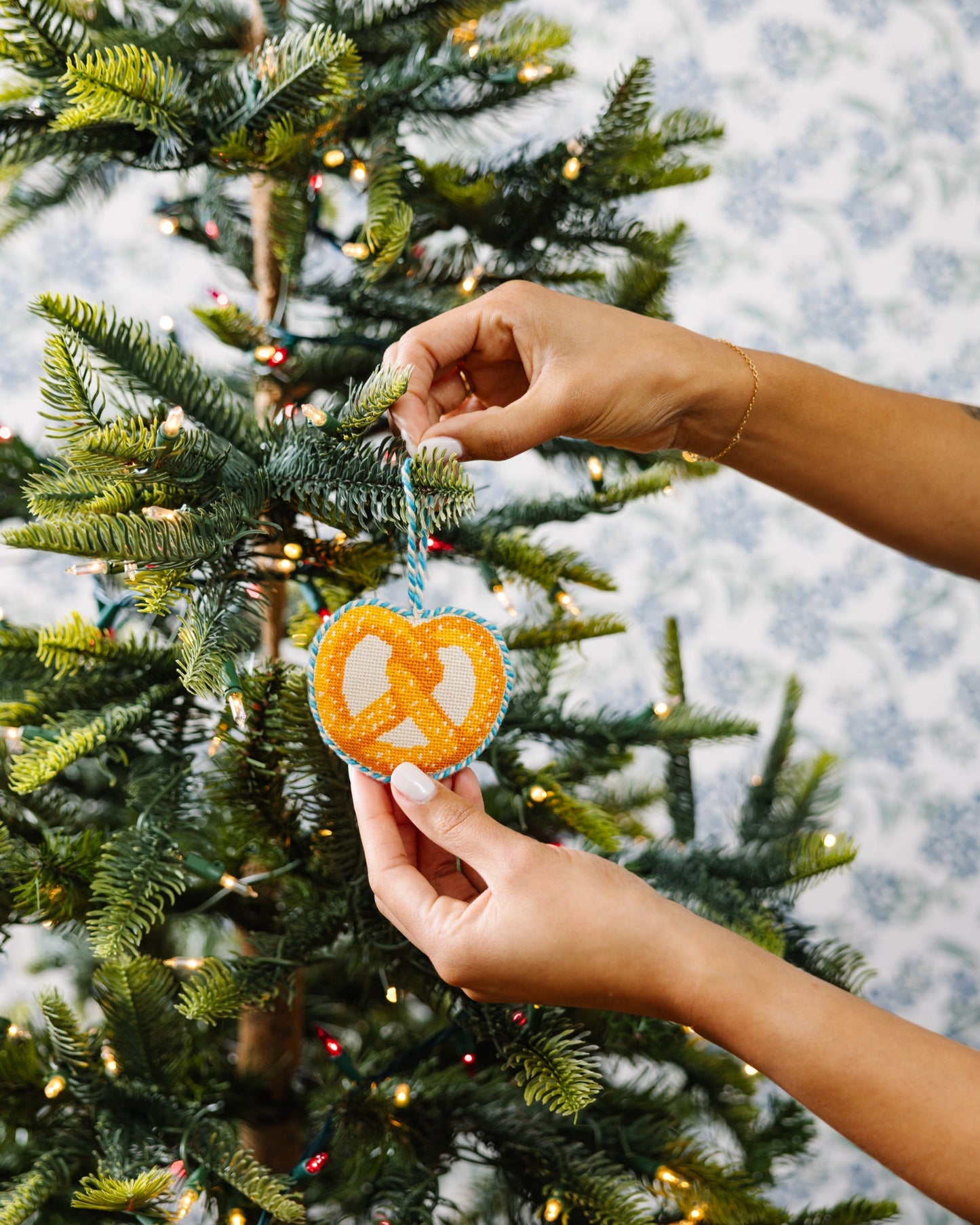 Person decorating a Christmas tree with a heart-shaped ornament.
