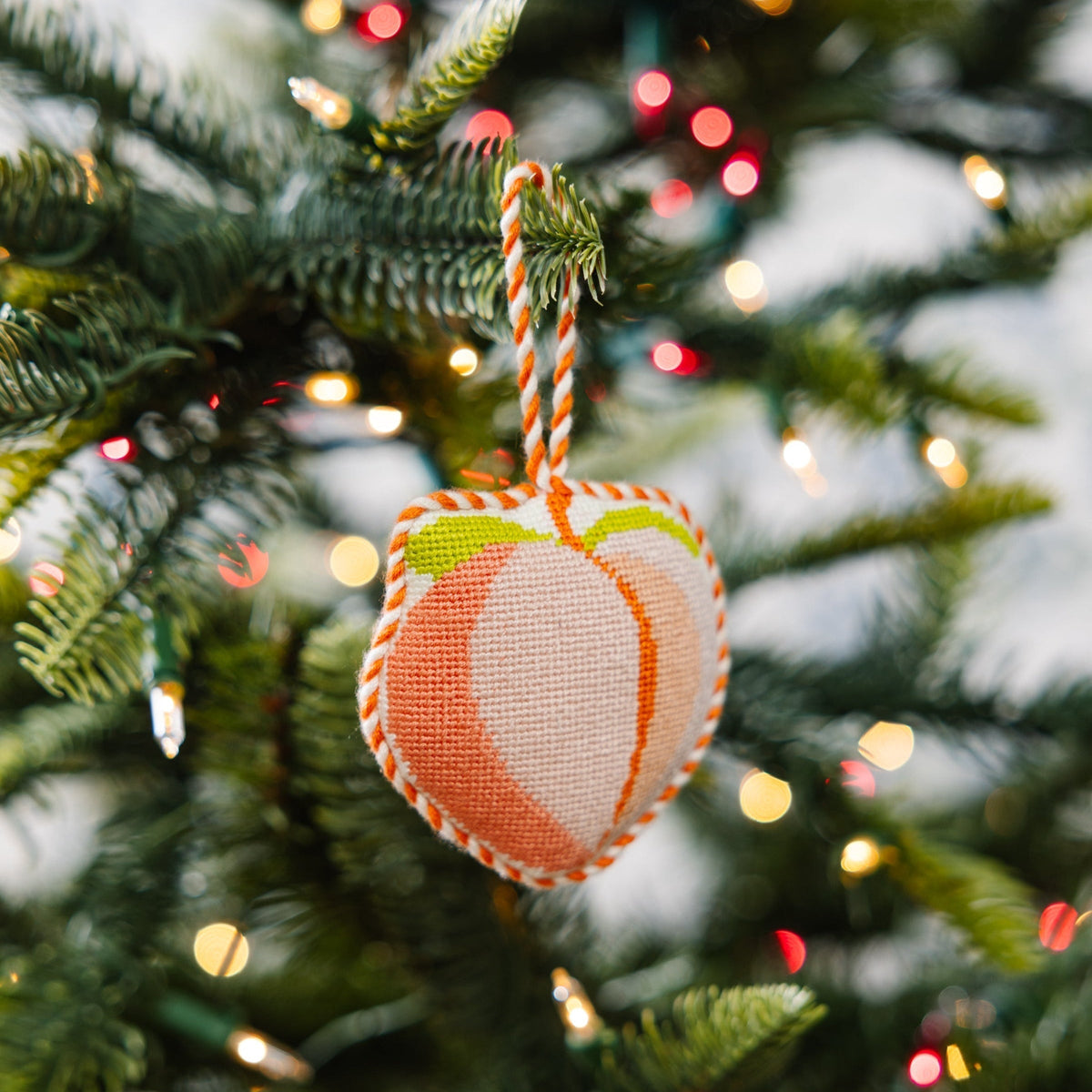 Decorative peach ornament on a Christmas tree with blurred lights in the background