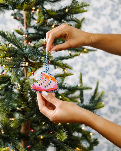 Person decorating a Christmas tree with a colorful ornament.