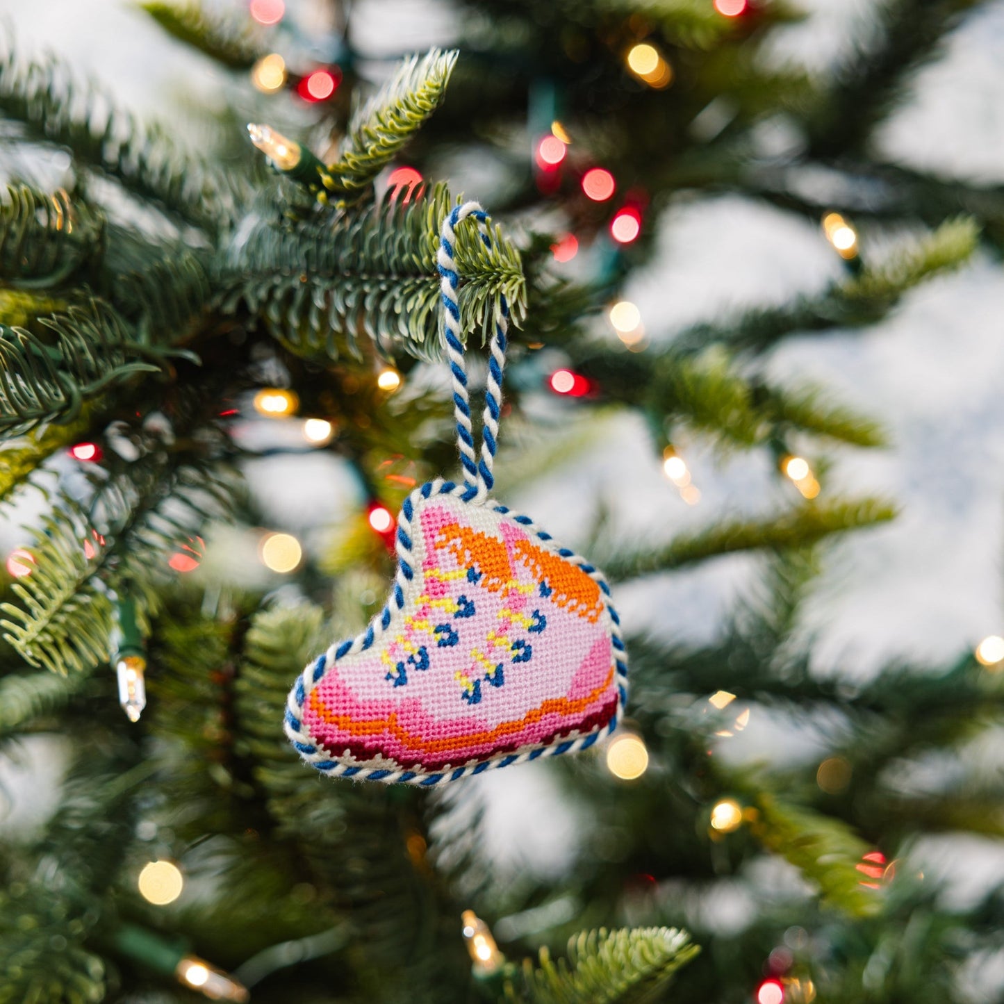 Decorative heart ornament on a Christmas tree with lights in the background