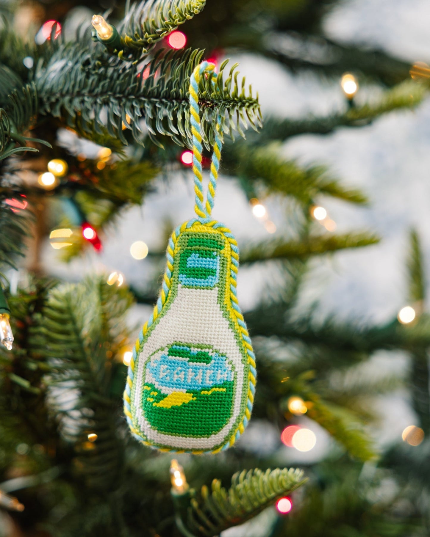 Decorative bottle ornament on a Christmas tree with lights in the background
