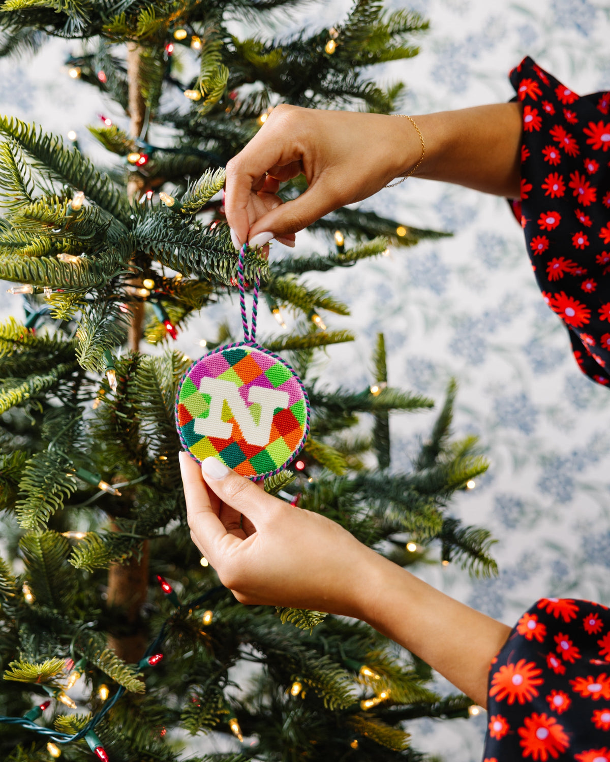 Person decorating a Christmas tree with a colorful ornament.