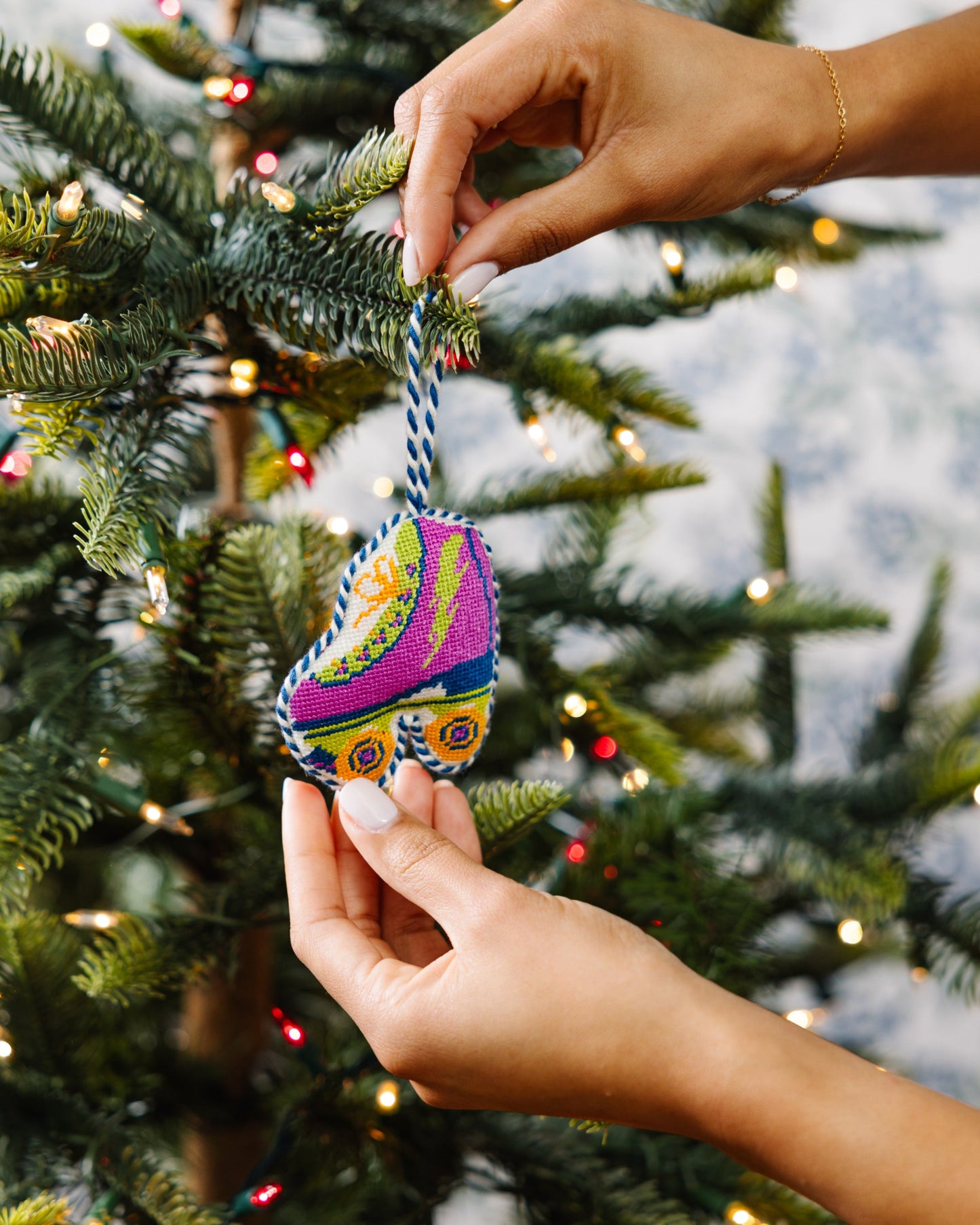 Colorful ornament being hung on a Christmas tree