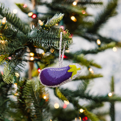 Decorative eggplant ornament on a Christmas tree with lights.