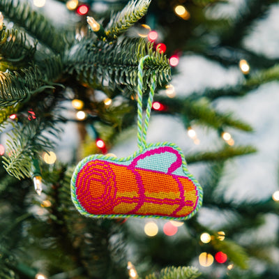Decorative log ornament on a Christmas tree with lights in the background