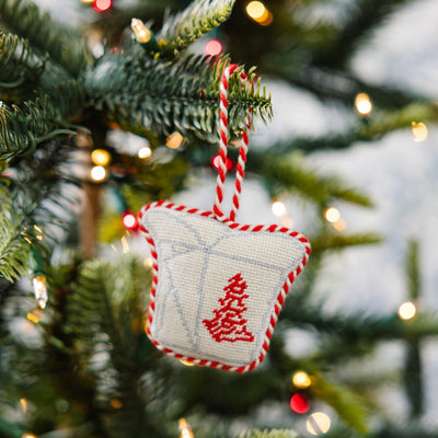Decorative Christmas ornament with red tree design on a Christmas tree with lights.