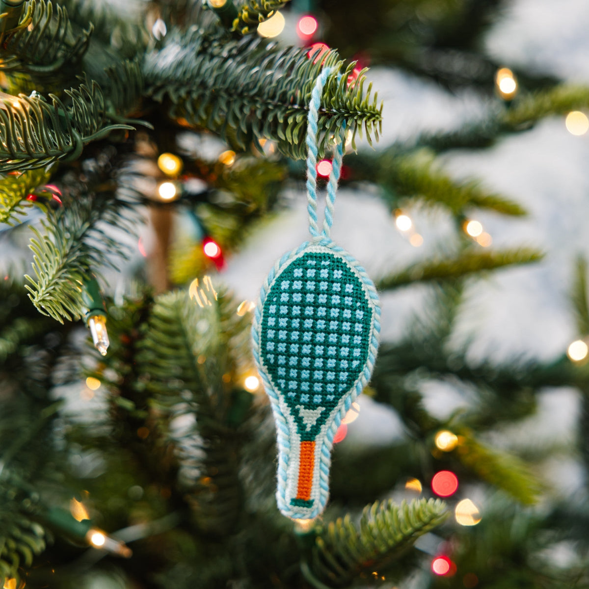Tennis racket ornament on a Christmas tree with blurred lights in the background