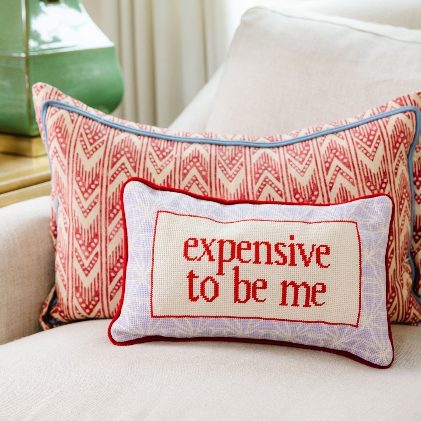 Decorative pillow with 'expensive to be me' text on a couch