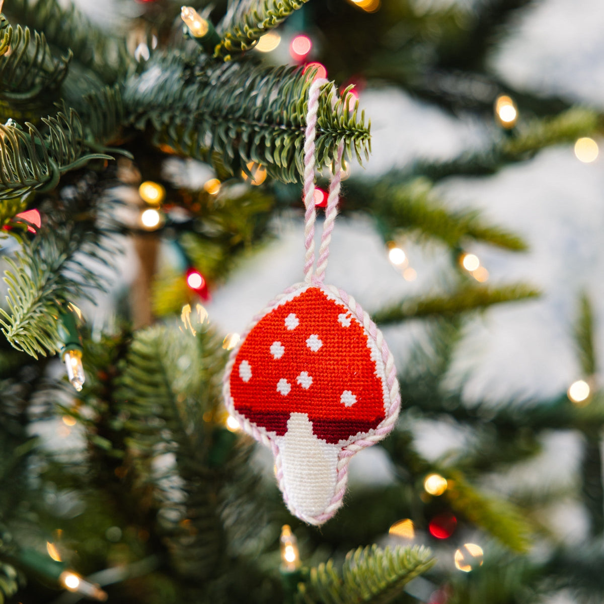 Red and white mushroom ornament on a decorated Christmas tree