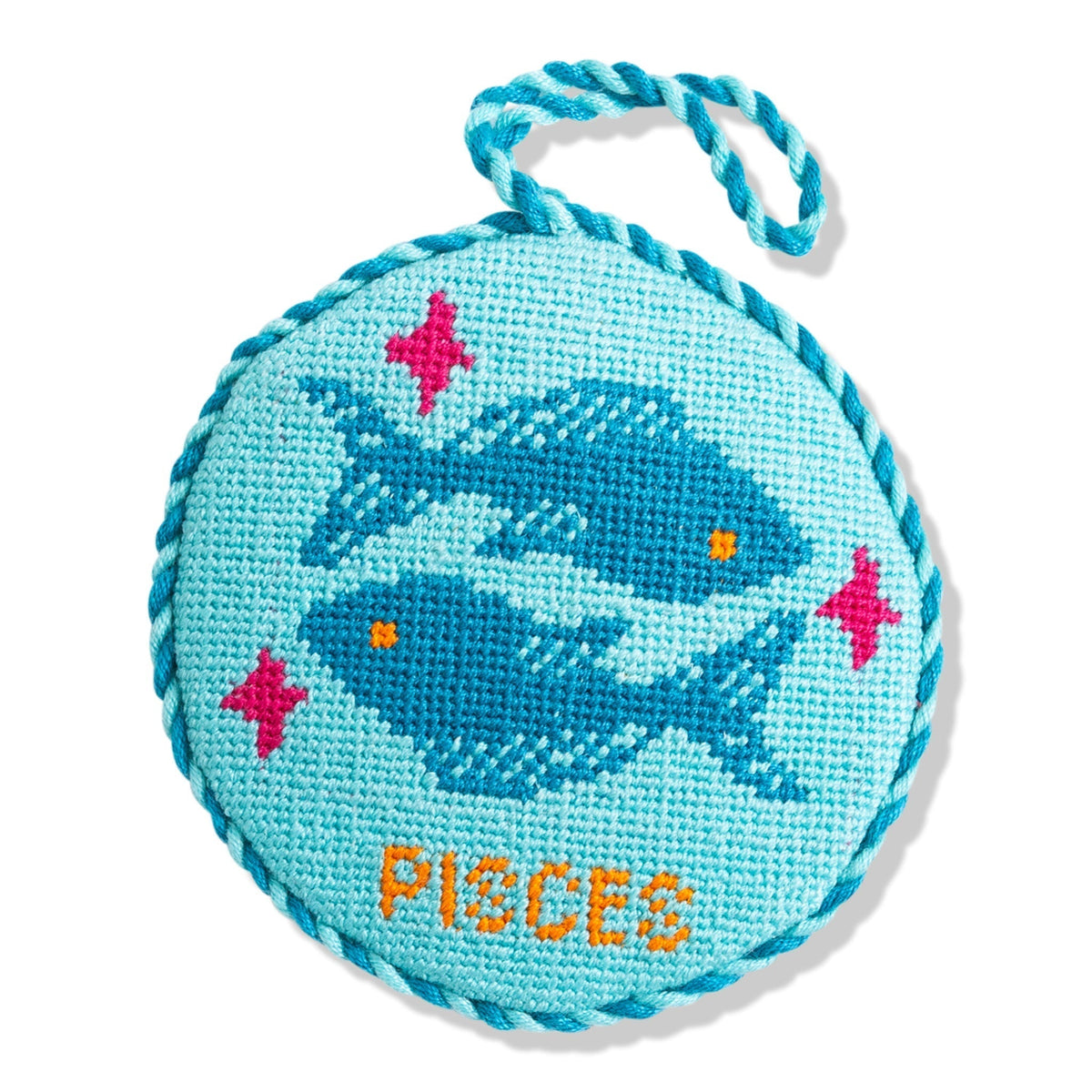 Round blue needlepoint toy with whale design and 'PIECES' text on a white background