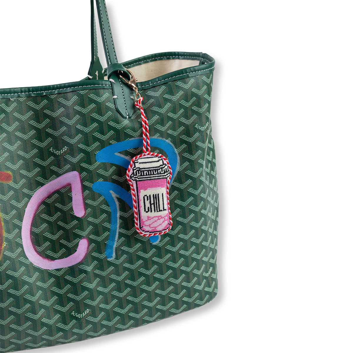 Green patterned tote bag with a colorful charm on a white background