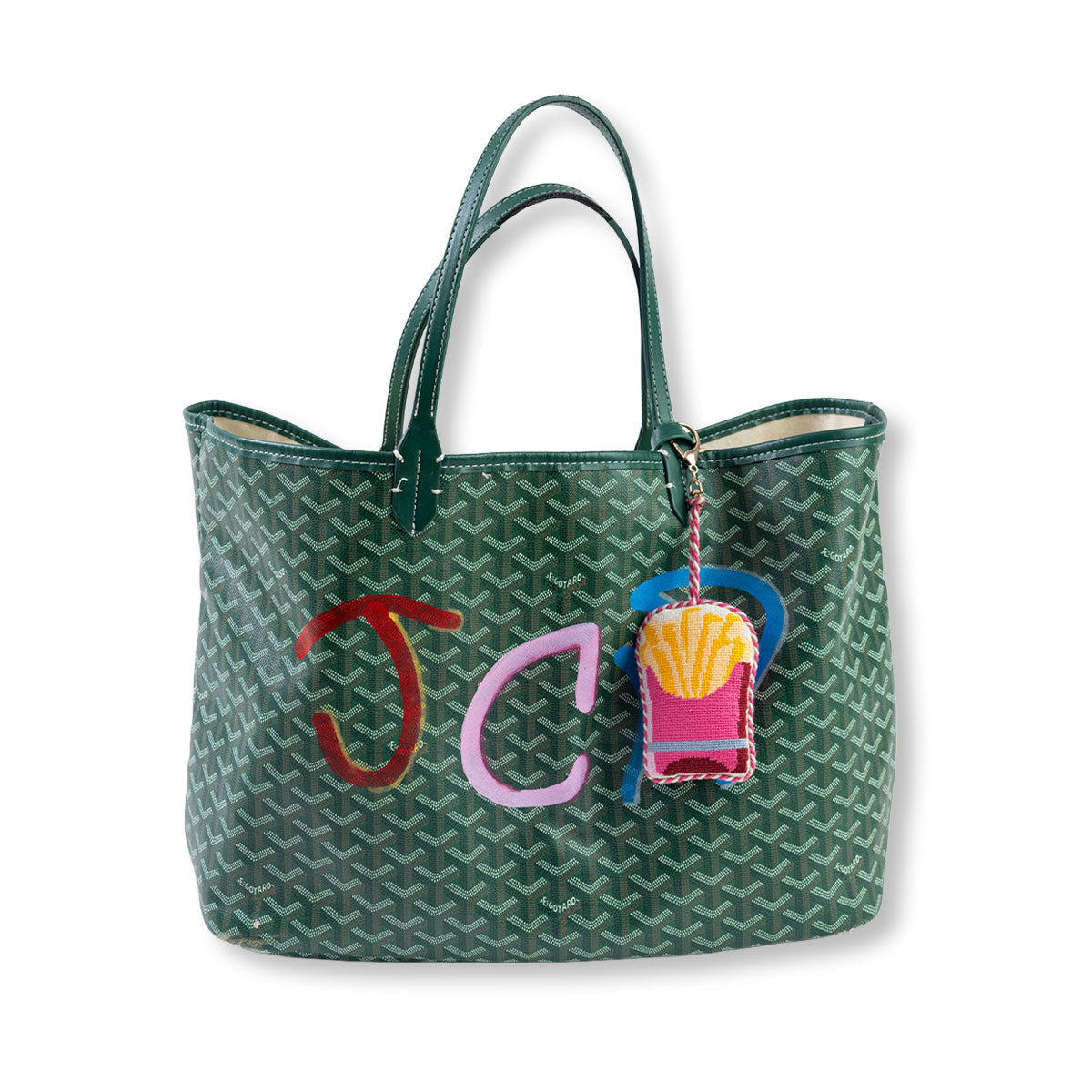 Green patterned tote bag with colorful 'JC' initials and a French fry charm on a white background