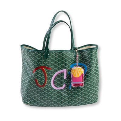 Green patterned tote bag with colorful 'JC' initials and a French fry charm on a white background