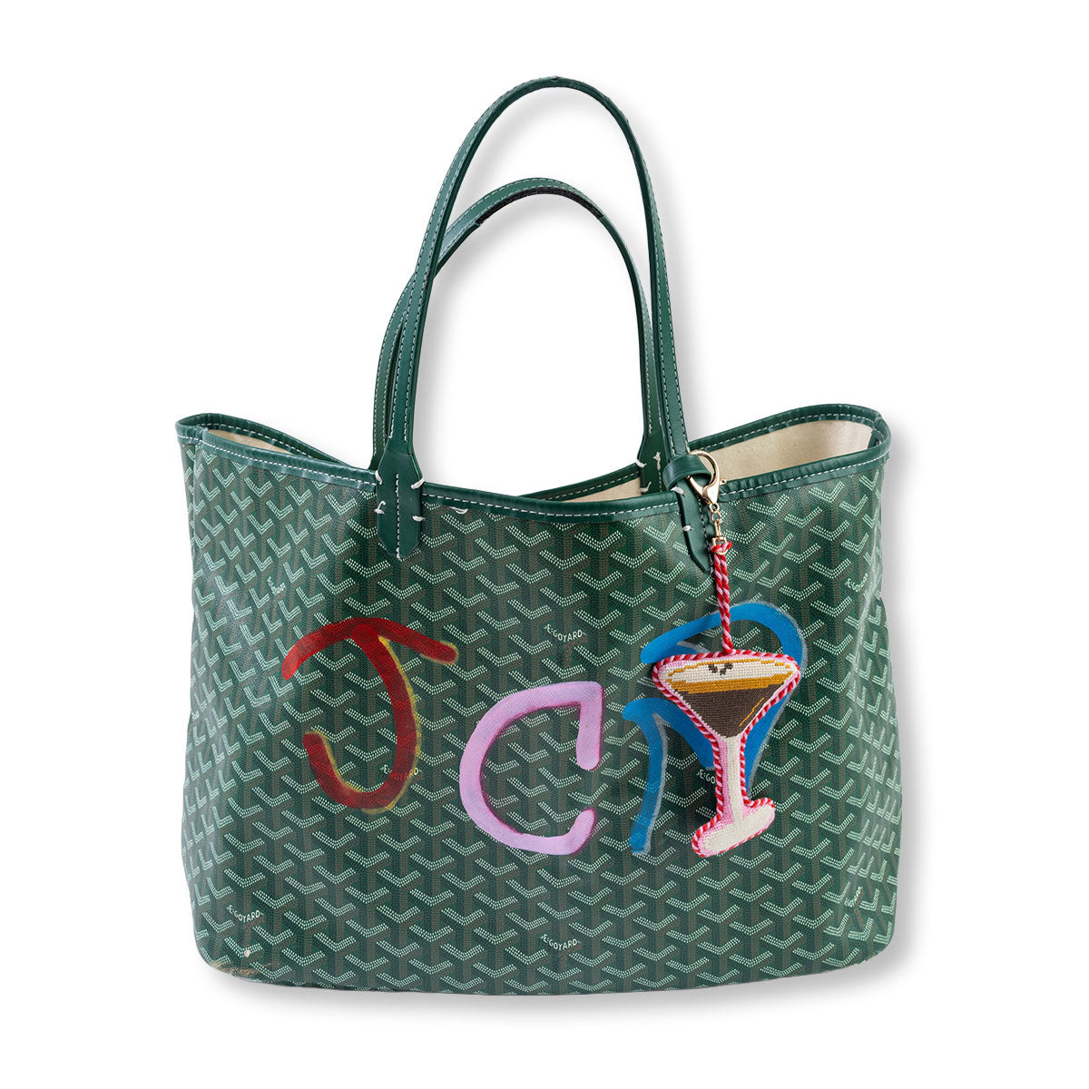 Green patterned handbag with colorful 'JCL' and martini glass charm on a white background