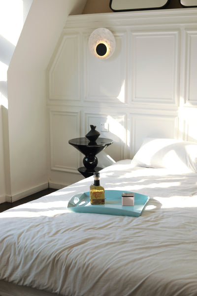 Vinidec medium curvy serving tray in baby blue, styled on a white bed with luxury room accessories in a bright bedroom setting