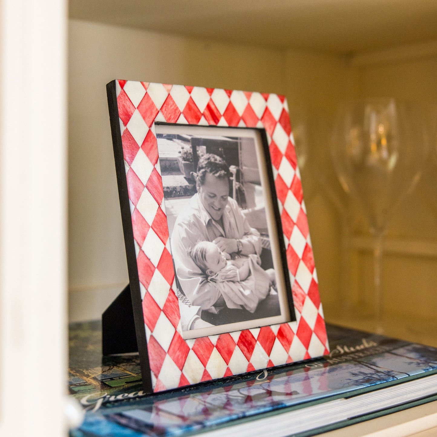 Red and white checkered picture frame with a photo of a woman holding a baby on a shelf.