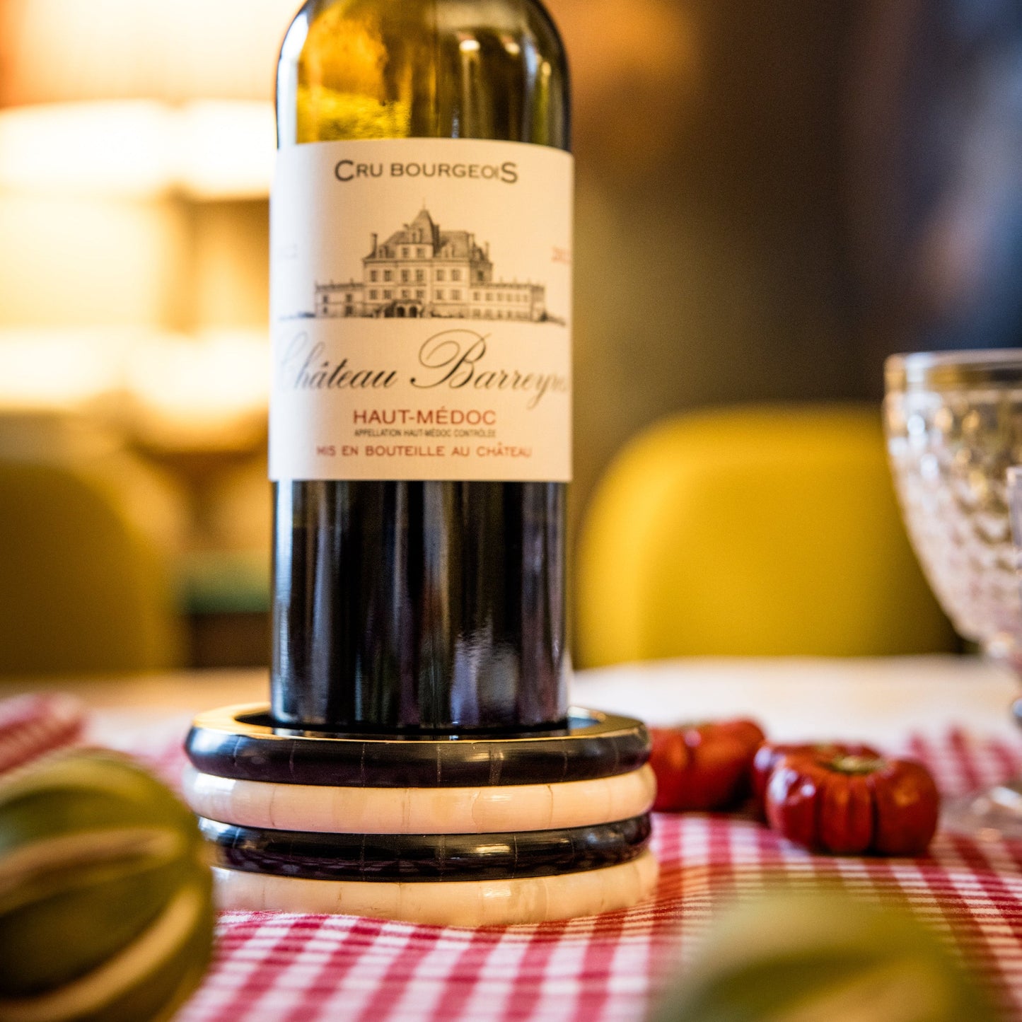 Bottle of Château Barrois wine on a coaster with decorative pumpkins on a checkered tablecloth.