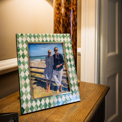 Framed photo of a couple on a table with a lamp in the background