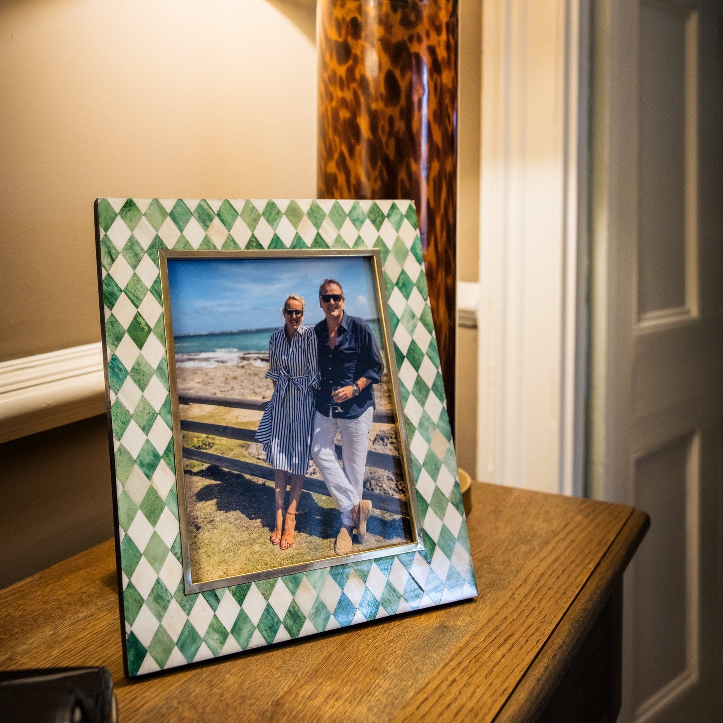 Framed photo of a couple on a table with a lamp in the background